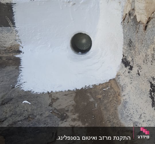 צינור מתכת בקיר עם איטום לבן סביבו